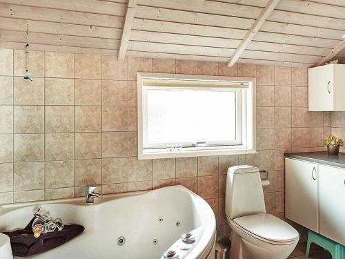 ein Bad mit einer Badewanne, einem WC und einem Fenster in der Unterkunft Holiday home Store Fuglede V in Store Fuglede