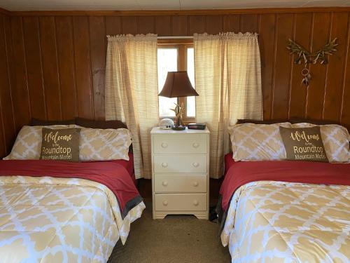 a bedroom with two beds and a nightstand and a window at Roundtop Mountain Vista - Cabins and Motel in Thermopolis