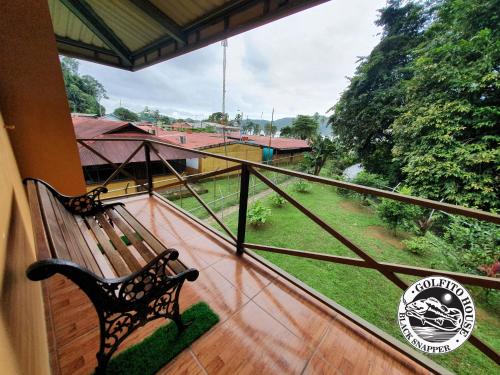 a bench on a balcony with a view of a field at Black Snapper House in Golfito