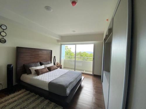 a bedroom with a large bed and a large window at Cozy apartment near to Costa Rica Airport in Heredia