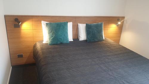 a bed with two green pillows on top of it at The Strand in New Plymouth