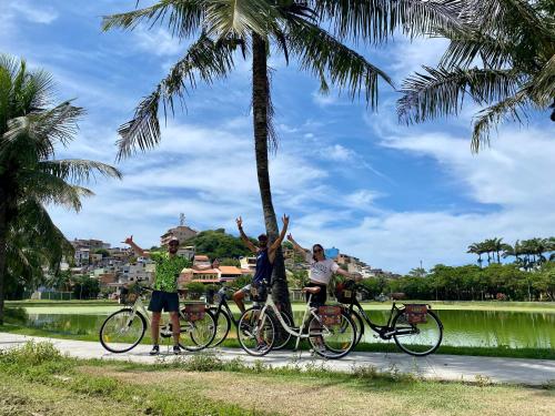 a group of people standing next to their bikes under a palm tree at A Coroa Hostel & Pousada in Arraial do Cabo