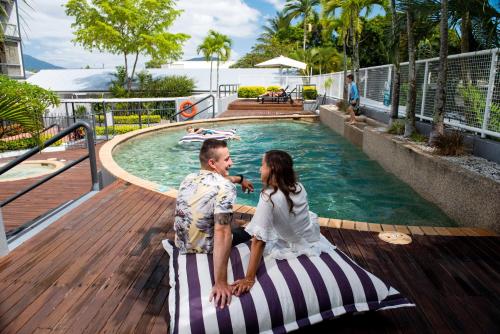 a man and a woman sitting on a striped blanket next to a swimming pool at Sunshine Tower Hotel in Cairns