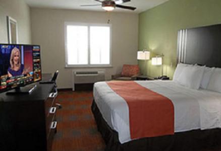 a hotel room with a bed and a flat screen tv at Quality Inn & Suites Victoria East in Victoria