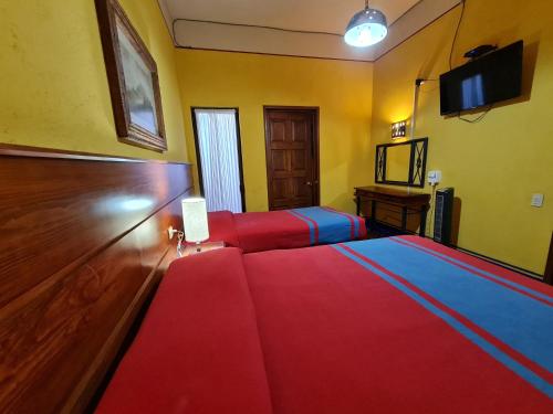 una camera da letto con due letti e una TV a schermo piatto di Hotel Suites Del Centro a Città di Oaxaca