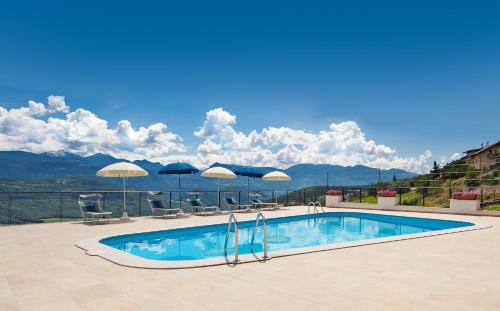 a swimming pool with umbrellas and a view of mountains at Pension Christl in Caldaro