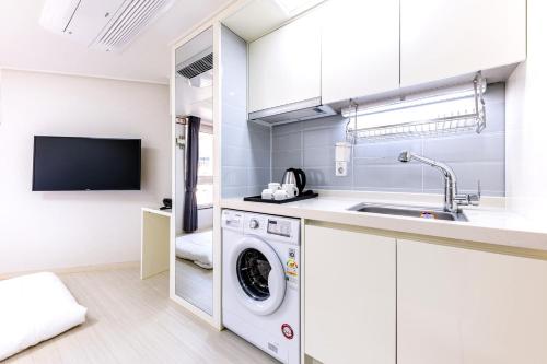 a kitchen with a washing machine and a sink at Shin Shin Hotel Seogwipo in Seogwipo
