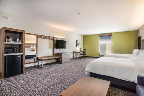 a hotel room with a bed and a flat screen tv at Holiday Inn Express & Suites Tulsa East - Catoosa by IHG in Catoosa