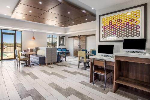 a lobby with tables and chairs and a large painting on the wall at Holiday Inn Express & Suites Tulsa East - Catoosa by IHG in Catoosa