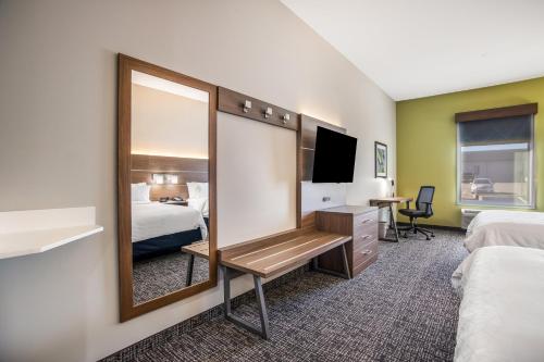 a hotel room with a mirror and a bed and a desk at Holiday Inn Express & Suites Tulsa East - Catoosa by IHG in Catoosa