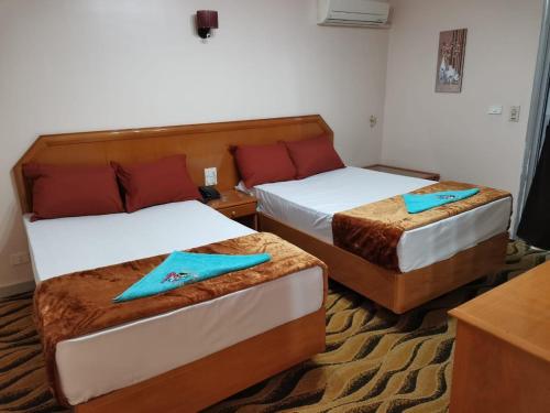 - 2 lits dans une chambre d'hôtel avec des serviettes bleues dans l'établissement فندق جراند كليوباترا دمنهور, à Damanhûr