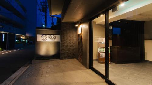 a building with glass doors on a street at night at Meldia Stay Nijojo IWAGAMI in Kyoto