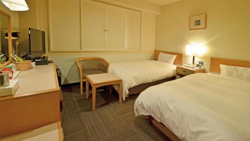 a hotel room with two beds and a desk at Omura Central Hotel in Omura