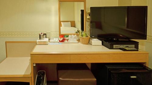 a desk with a television on top of a room at Omura Central Hotel in Omura