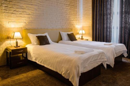 2 camas en una habitación de hotel con 2 lámparas en Usman, en Samarkand