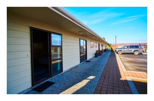 a building with a sidewalk next to a parking lot at Greymouth Seaside TOP 10 Holiday Park in Greymouth