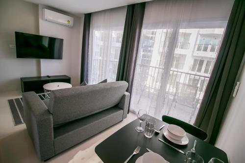 a living room with a couch and a table and a window at Mantra Beach Condominium Suite - Mae Phim in Ban Tha Fat