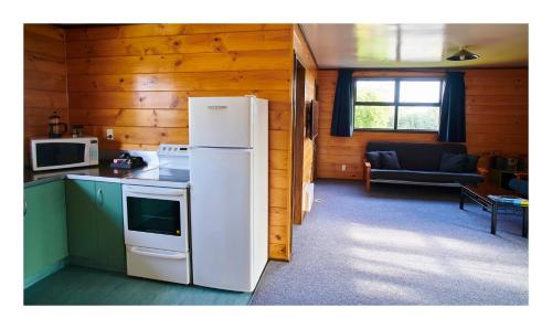 a kitchen with a refrigerator and a living room at Greymouth Seaside TOP 10 Holiday Park in Greymouth