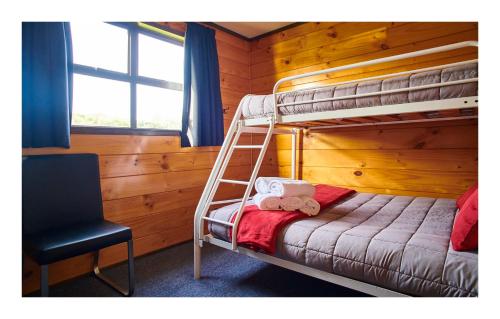 a bedroom with a bunk bed and a chair at Greymouth Seaside TOP 10 Holiday Park in Greymouth