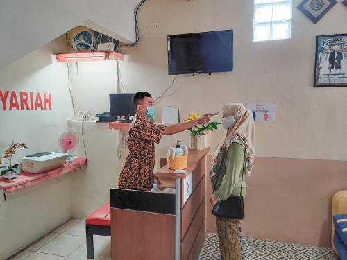 a woman is standing at a cash register at Ayuning Guest House Syariah Semarang Mitra RedDoorz in Semarang