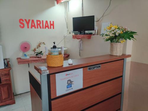 a counter with flowers on top of a dresser at Ayuning Guest House Syariah Semarang Mitra RedDoorz in Semarang