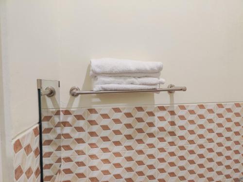 a bathroom with three towels on a towel rack at Ayuning Guest House Syariah Semarang Mitra RedDoorz in Semarang