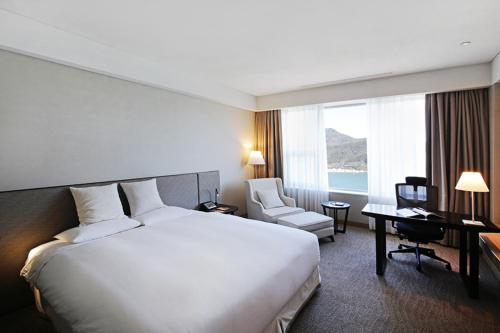 a hotel room with a large white bed and a desk at Geoje Samsung Hotel in Geoje 