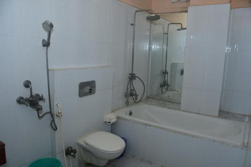 a bathroom with a tub and a toilet and a sink at Hotel Om International in Bodh Gaya