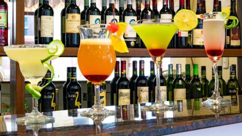 four cocktails on a bar with bottles of wine at Sapa Horizon Hotel in Sa Pa