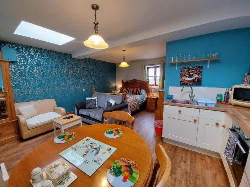 cocina y sala de estar con mesa y sofá. en Dog friendly detached studio - Up to 3 Guests can stay - Only 3 Miles from Lyme Regis - Large shower ensuite -Kitchen - Small fenced garden - Free private parking, en Axminster