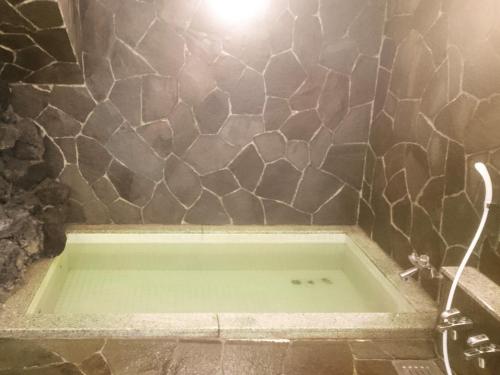 a bath tub in a bathroom with a stone wall at Hotel Madam Mirei in Iiyama