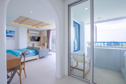 a bedroom with a bed and a desk and a glass door at Costa Beach Residence & Jacuzzi in Sattahip