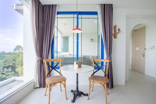a table and two chairs in a room with a window at Costa Beach Residence & Jacuzzi in Sattahip