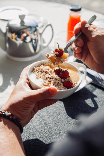 een persoon die een kom ontbijtgranen met aardbeien vasthoudt bij Auberge Kallisté - Eco Label in Porto Pollo