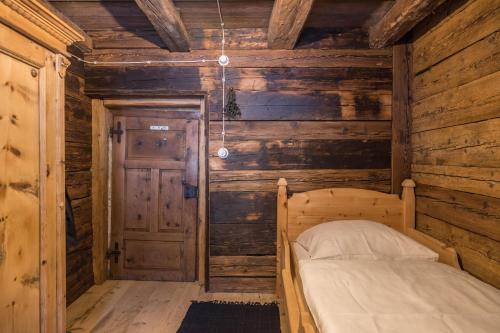 a bed in a room with a wooden wall at Tannhäuser Mountain Chalet in Predoi