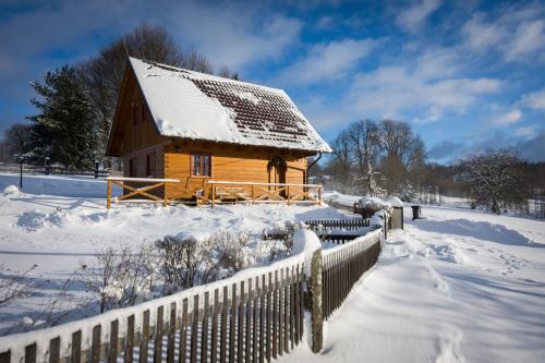 a wooden cabin in the snow with a fence at Roubenka Háj in Jindřichovice