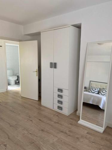 a white bedroom with a mirror and a bed at Libertad 8 alojamiento turistico in Jaén