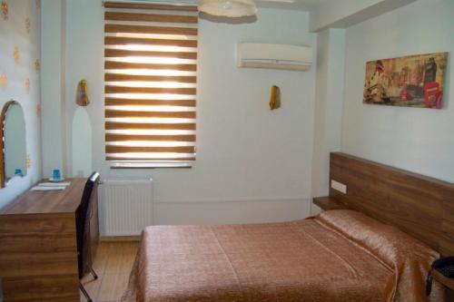 1 dormitorio con cama, escritorio y ventana en Yunus Hotel, en Gaziantep