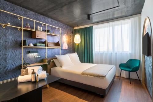 a hotel room with a bed and a green chair at Aiden by Best Western Lorient Centre in Lorient