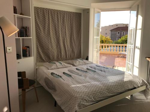 um quarto com uma cama e uma janela grande em Le louvre-terrasse-centre ville em Menton