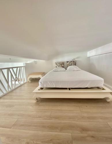 une chambre blanche avec un lit blanc et un escalier dans l'établissement Studio La Pietonne-plage-clim, à Menton