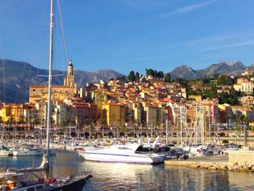 un groupe de bateaux amarrés dans un port avec une ville dans l'établissement Studio La Pietonne, à Menton