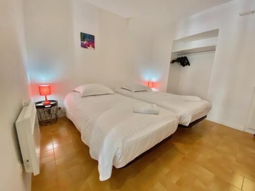 - 2 lits dans une chambre blanche avec 2 lampes dans l'établissement Les Logettes-plage-centre, à Menton