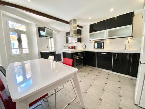 une cuisine avec une table blanche et des armoires noires dans l'établissement Les Logettes-plage-centre, à Menton