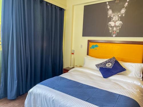 a bedroom with a large bed with blue curtains at Alice’s Home in Jinsha