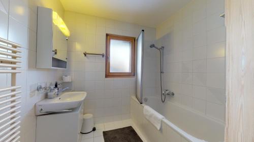 een witte badkamer met een wastafel en een douche bij Cozy apartment in Veysonnaz, close to the slopes of the 4 Valleys in Veysonnaz