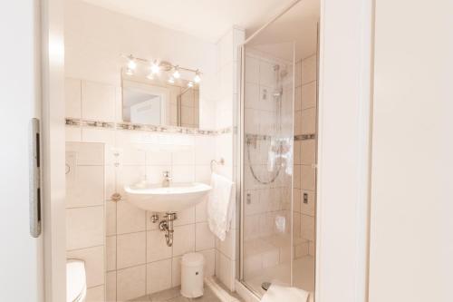 biała łazienka z umywalką i prysznicem w obiekcie Hotel- Restaurant Zum Hirsch w mieście Großenlüder