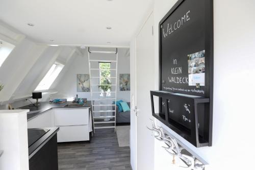 een keuken met witte kasten en een tv aan de muur bij Appartement Klein Waldeck in Velp