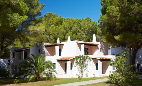 a white house with trees in front of it at Insotel Club Maryland in Playa Migjorn