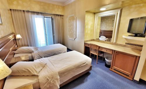 pokój hotelowy z dwoma łóżkami, biurkiem i lustrem w obiekcie Noufara w Pireusie
